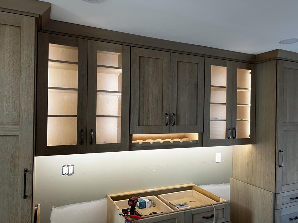 Dark wood glass-front cabinets and a wine rack lit from inside