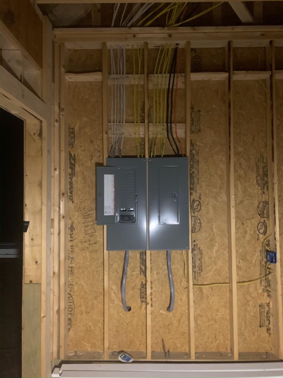 Two electrical panels with covers on a framed wall in new construction