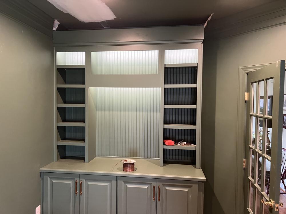 Green built-in shelves with lighting along the top
