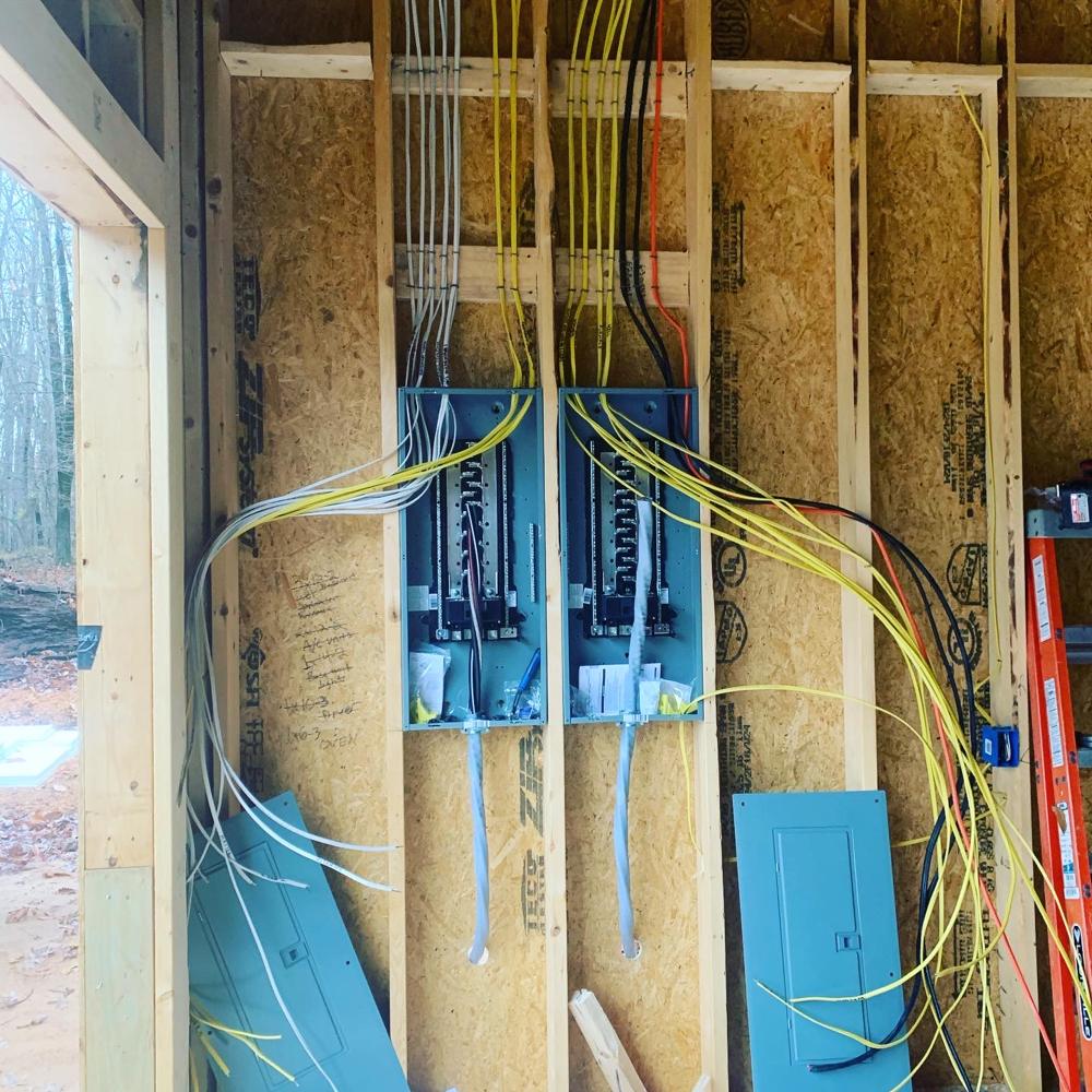 Neatly run cables feeding two new electrical panels on a framed wall