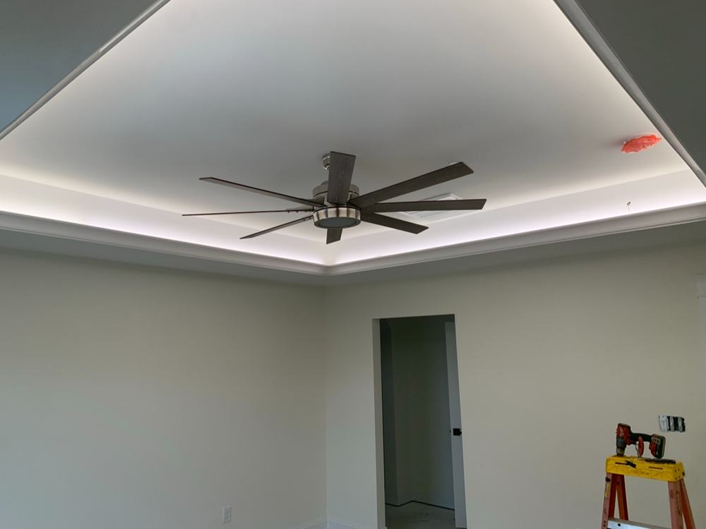 Glowing cove lighting around a tray ceiling with a ceiling fan